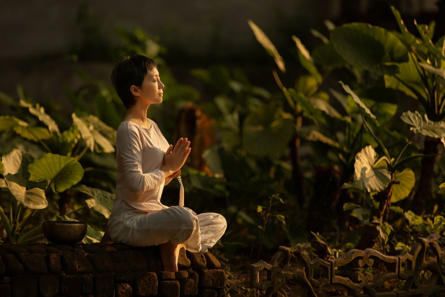 Woman meditating surrounded by plants